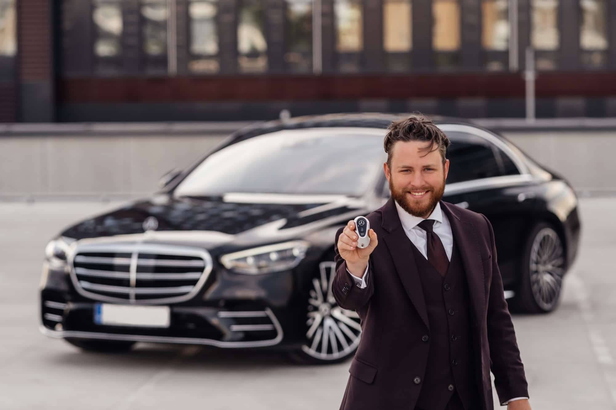Brussels, Belgium July 22, 2021 Mercedes Benz S500 AMG S class w223 brand new model is standing in the parking lot by a modern office in the background.Smiling limousine transfer driver with key in hand.